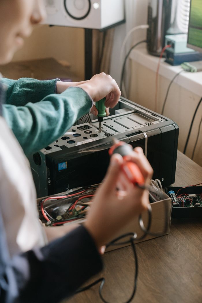 Crafting Captivating Headlines: Your awesome post title goes here Adults working together to repair a computer using tools like a screwdriver and soldering iron.