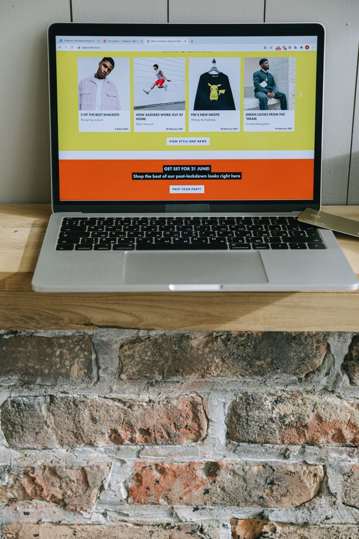 Mastering the First Impression: Your intriguing post title goes here A laptop on a wooden shelf showing a colorful online shopping webpage.